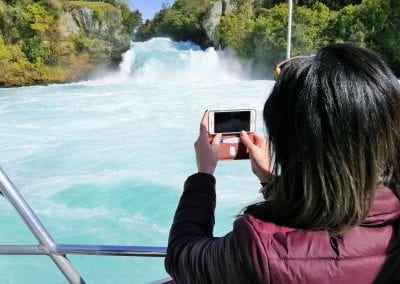 Lady taking photo of Huka Falls from boat